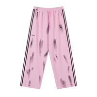 Pink sweatpants with black stripes and brushstroke pattern.