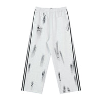White sweatpants with black stripes and paint splatters.